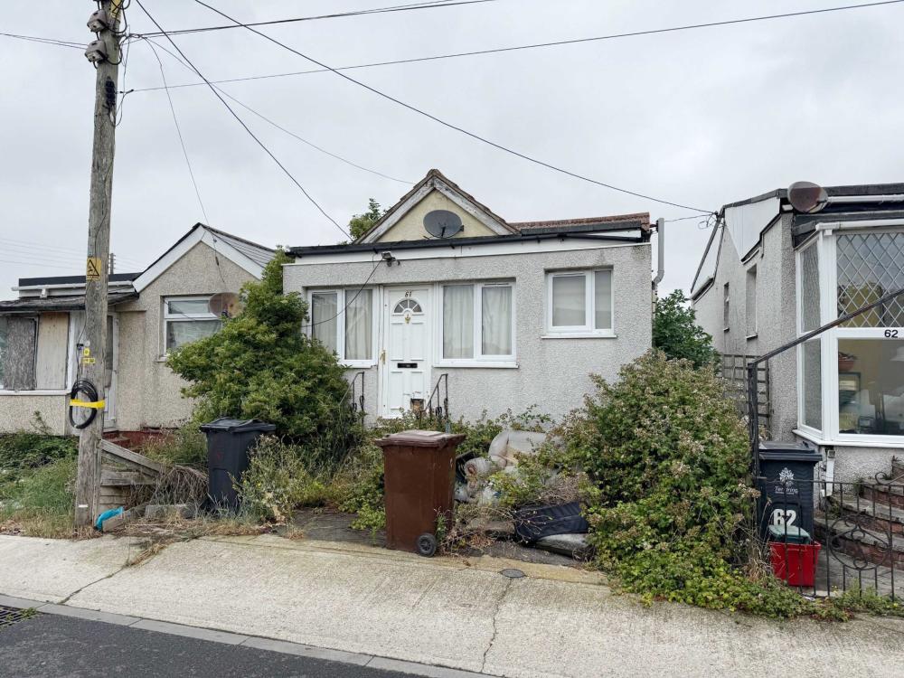 a grey colour stone built chalet bungalow with white front door. The sky is white grey.