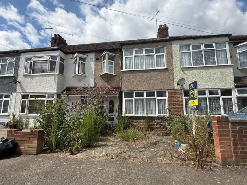 brown cladded mid terraced house set back from the road bheind a driveway. There are white framed windows on grround and first floor. White cloudy sky. 