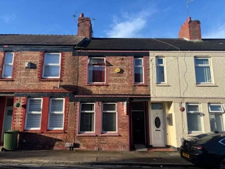 A row of terraced houses, with two being brown brick and the one on the right a cream brick. Blue sky above.