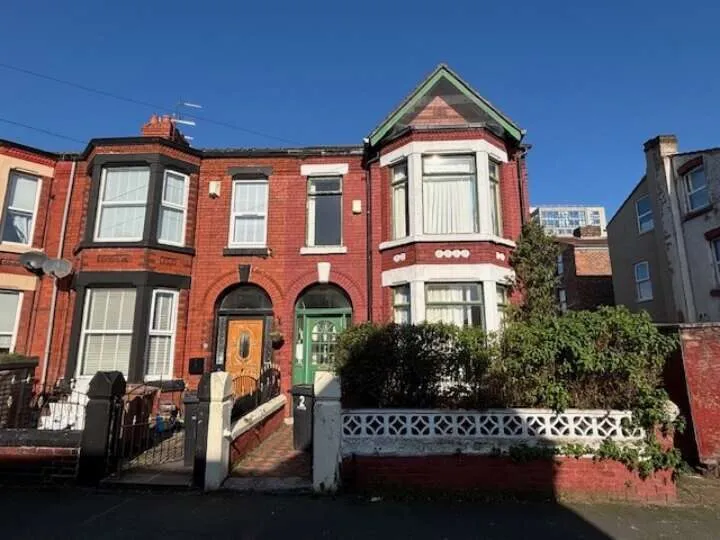 Brown brick end terrace period property over two floors behind white fence
