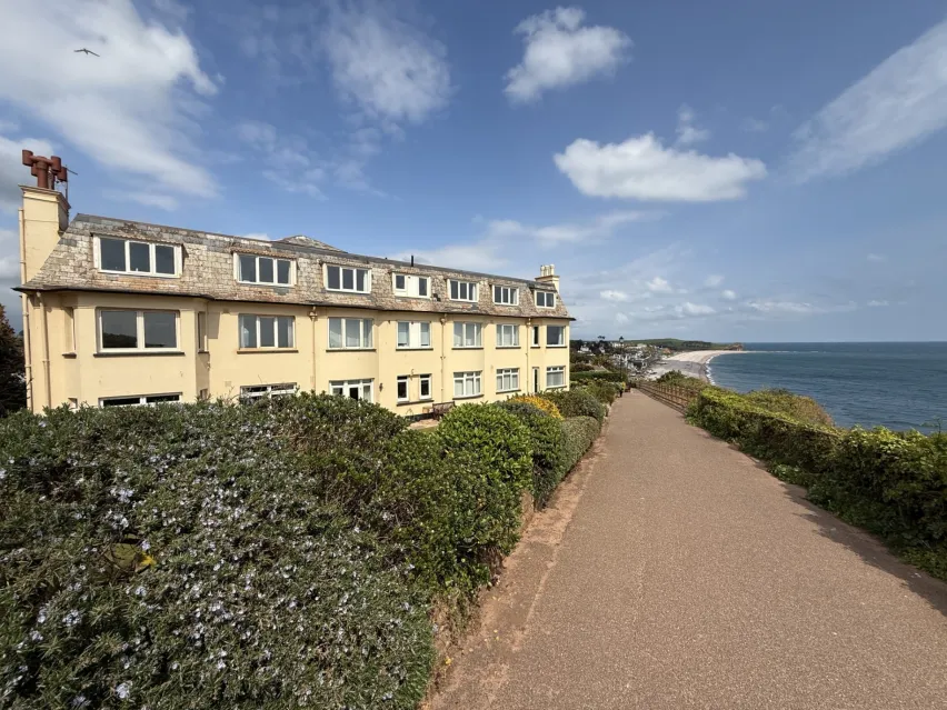 Large detached pale yellow building comprising of flats with sea view