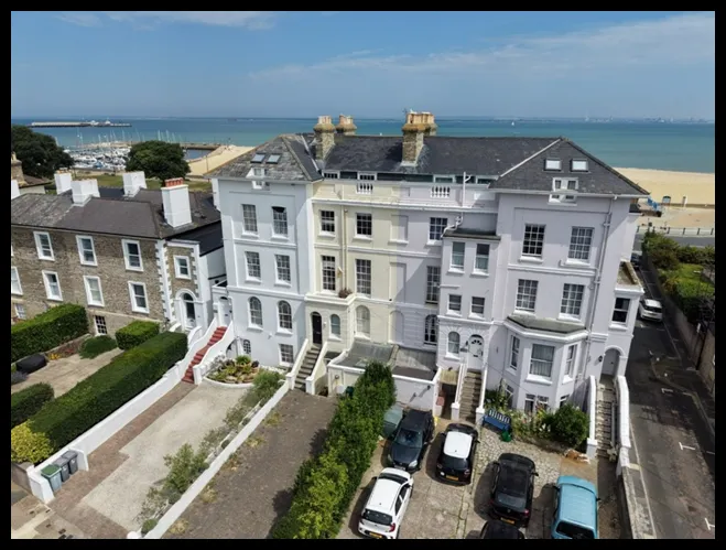 Row of 5 storey houses overlooking the seafront with blue sea and blue sky in the background