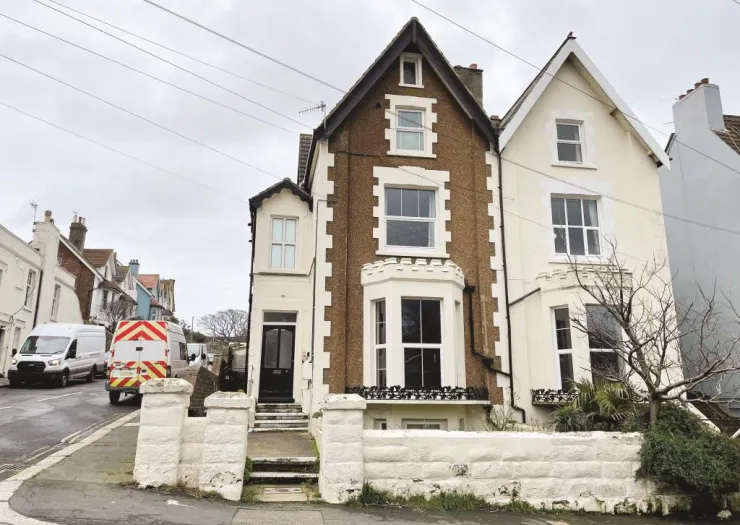Brown and white semi-detached house with bay window and low front wall.