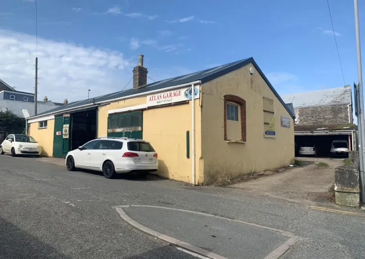 Atlas Garage, a light yellow building with cars parked outside, under a blue sky.
