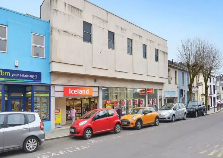 Iceland supermarket storefront on a UK high street with parked cars.
