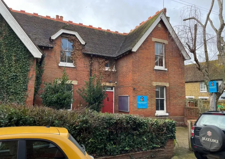Red brick two-story building with ivy covered walls, signage indicating "St Paul's House Nursery.