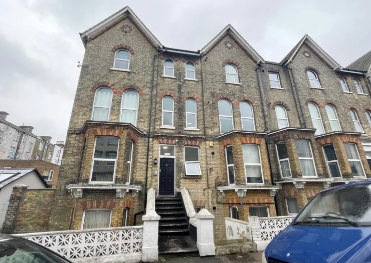 Brick apartment building with arched windows and white decorative wall.