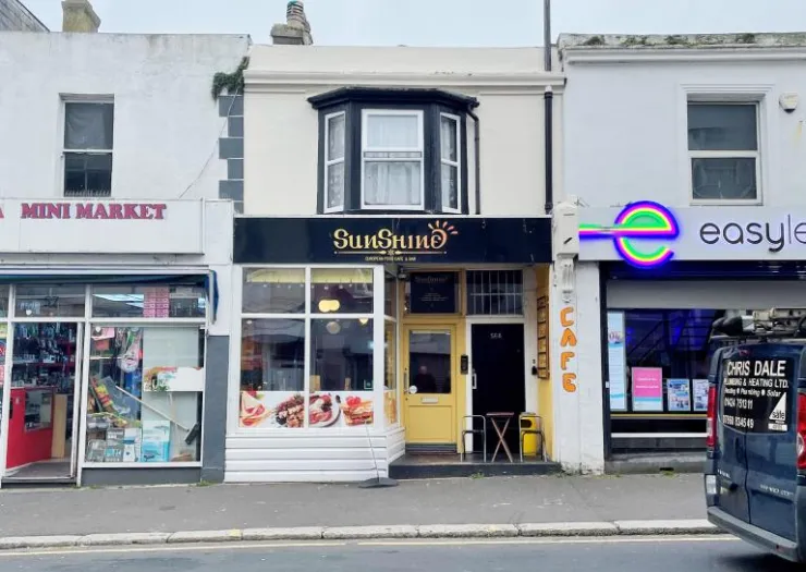 Sunshine" cafe storefront between a mini market and easylet shop.