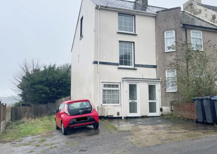 White two-story terraced house exterior with red car parked in front driveway.