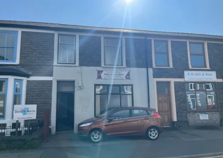 Space to be Creative" storefront with a parked car on a sunny day.