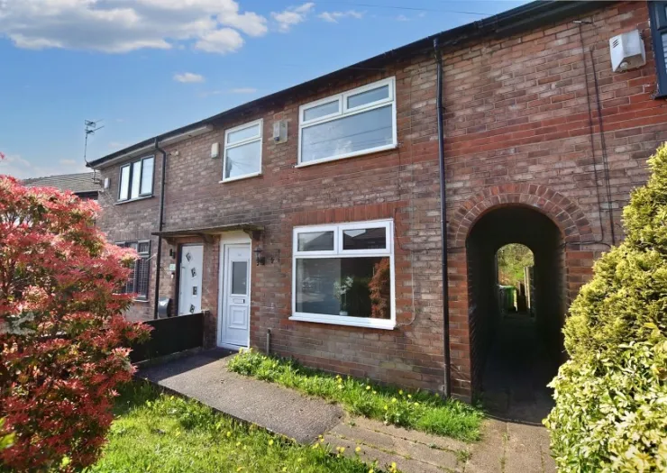 Red brick terraced house exterior with white door and windows, walkway, and arched side passage.