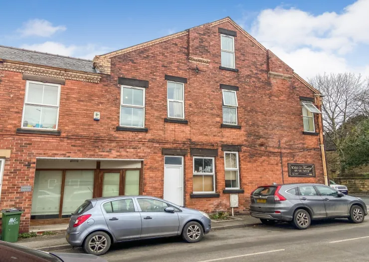 Red brick multi-story building with "House of Trends" sign, parked cars on street.