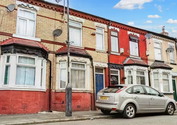 Row of terraced houses in varying colors, with a silver car parked on the street.
