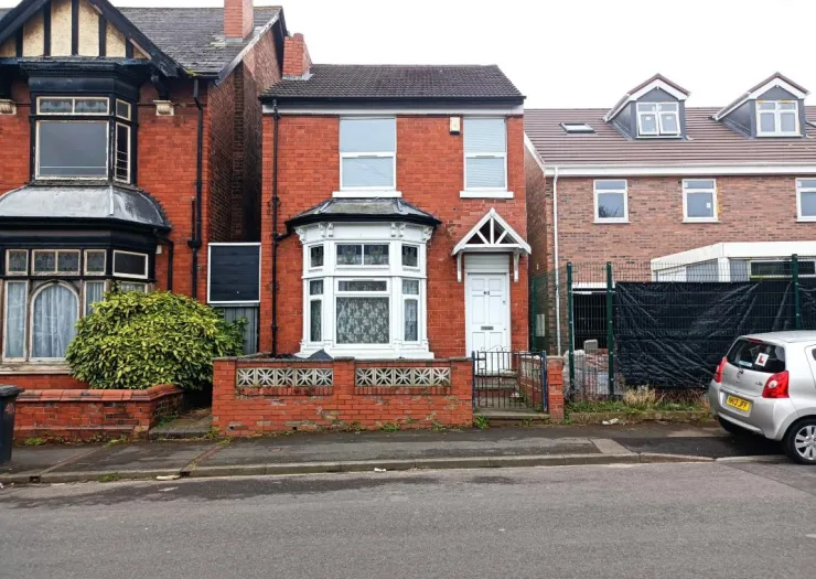 Red brick house with white bay window and small porch.