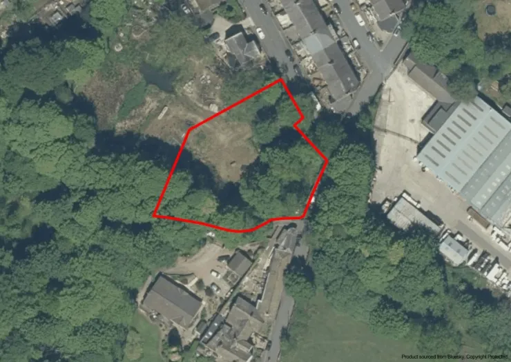 Aerial view of land outlined in red, surrounded by trees and buildings.