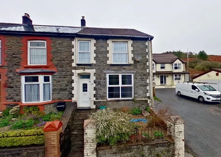 Stone terraced house with white front door and red brick accents.