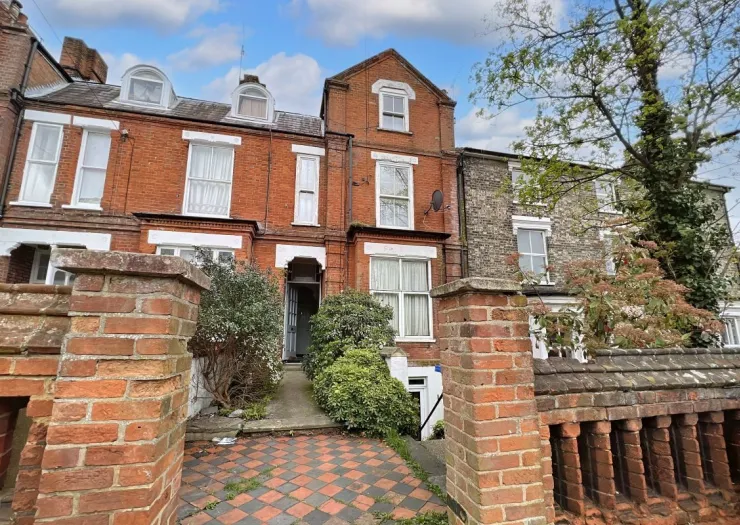 Red brick terraced house exterior with checkered walkway and brick wall.