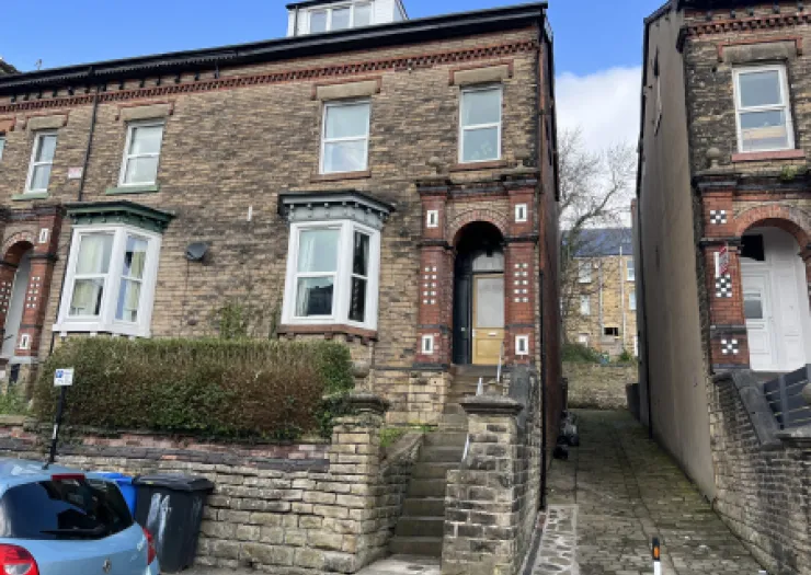 Brick terraced house exterior with decorative porch, bay windows, and stone steps.
