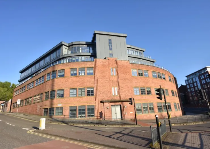 Modern red brick apartment building with curved facade and rooftop terrace.