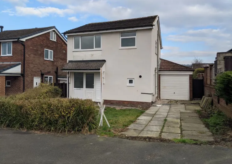White semi-detached house with attached garage and paved driveway.