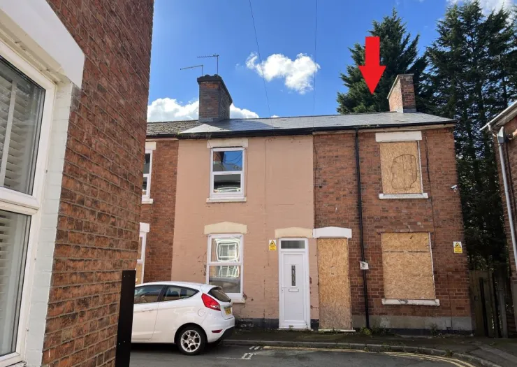 Brick terraced house with boarded-up windows and a visible chimney.