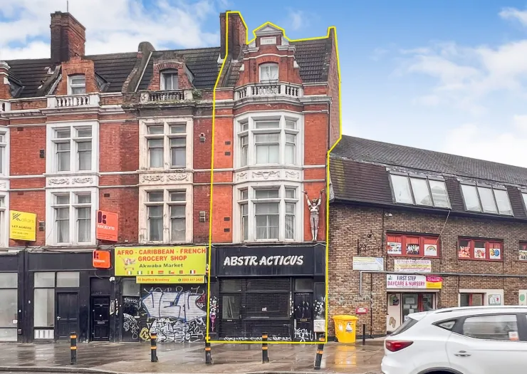 Red brick commercial building with shops on ground floor and flats above.