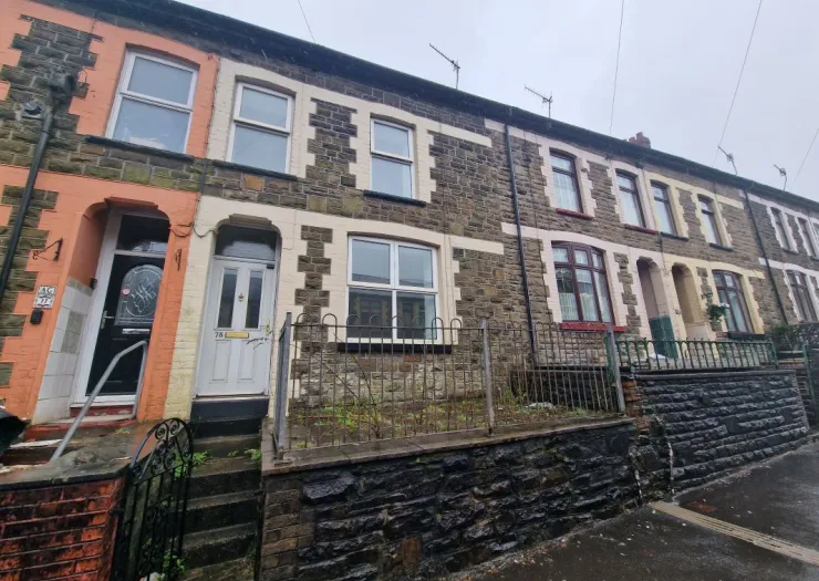 Stone terraced houses with fenced front gardens, one with a distinctive orange facade.