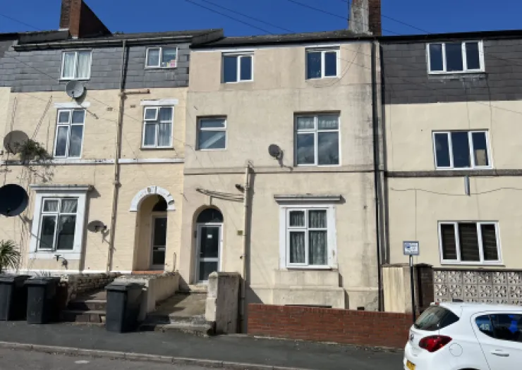 Cream-colored terraced house exterior with arched entryway and white-framed windows.