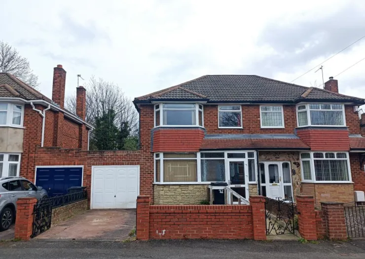 Red brick semi-detached house with attached garage and front garden.