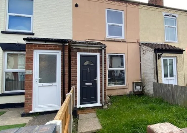 Red brick house with palm trees in front yard, under a blue sky.