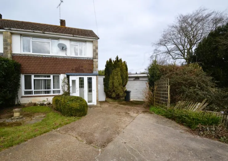 Two-story house with white siding, brown tiled facade, front garden, driveway, and detached garage.