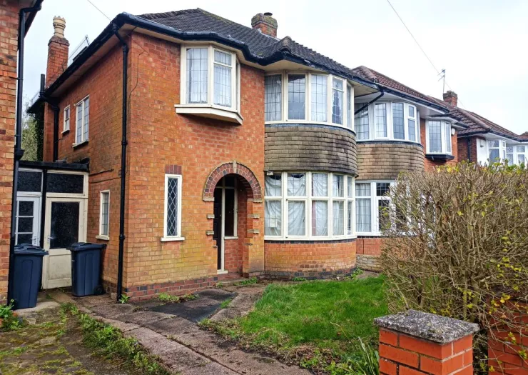 Red brick house with curved bay windows and arched doorway.