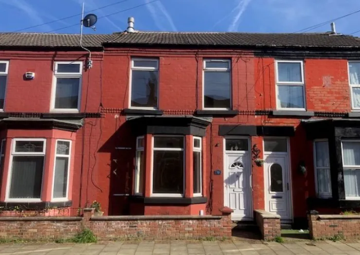 Red terraced house with bay window and white front door.