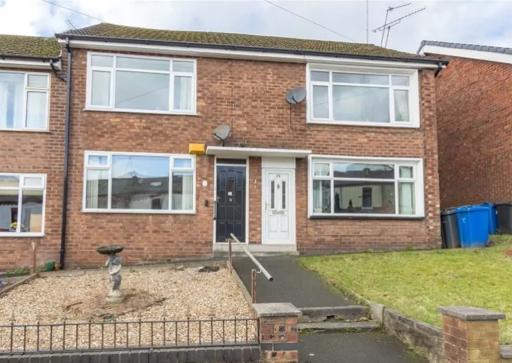 Red brick duplex with white-framed windows, a small front garden, and a paved walkway with a handrail.