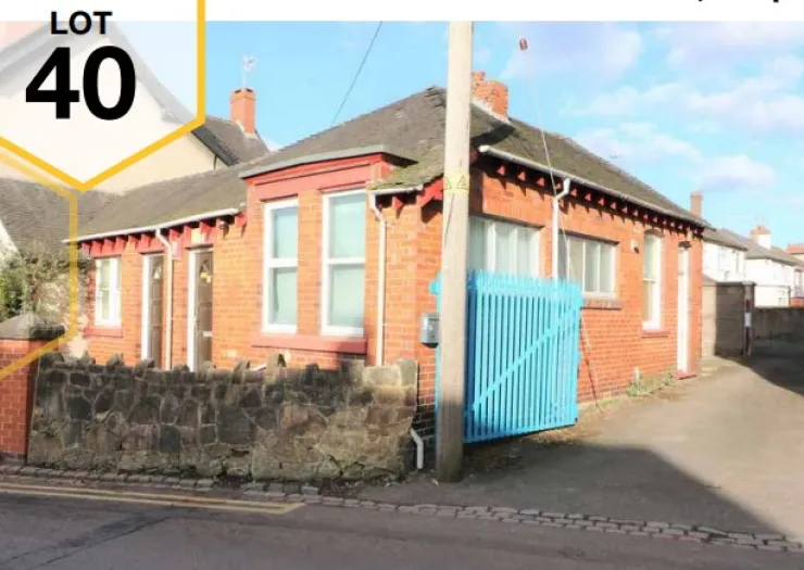 Red brick detached house (Lot 40) with blue gate and stone wall.
