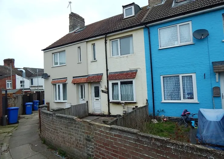Row of terraced houses, one beige, one light blue, with small front gardens and a low brick wall.