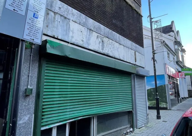 Green metal storefront security shutters closed on a commercial building.