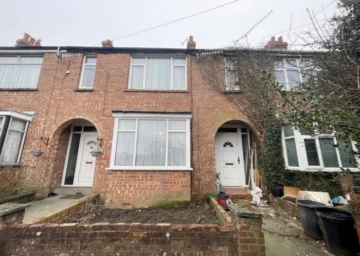 Red brick terraced house exterior with white bay windows and front door.