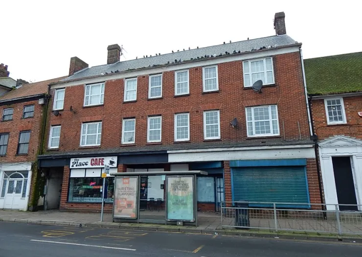Two-story red brick building with "The Place Cafe" and a bus stop in front.