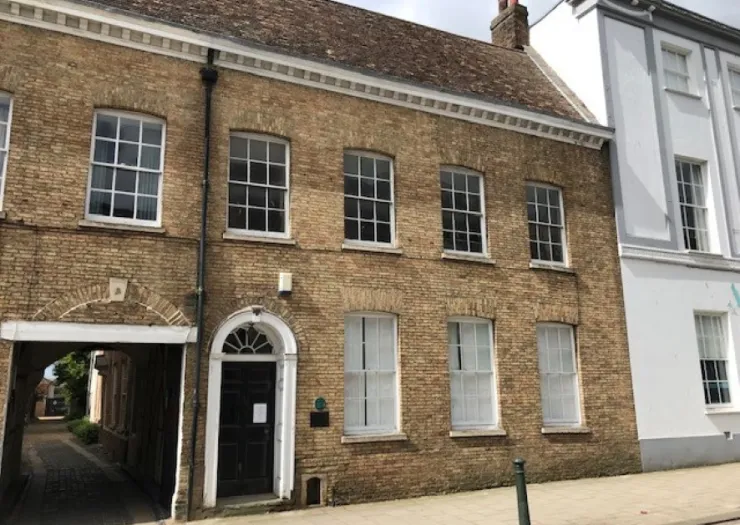 Tan brick office building with arched entryway and white-trimmed windows.