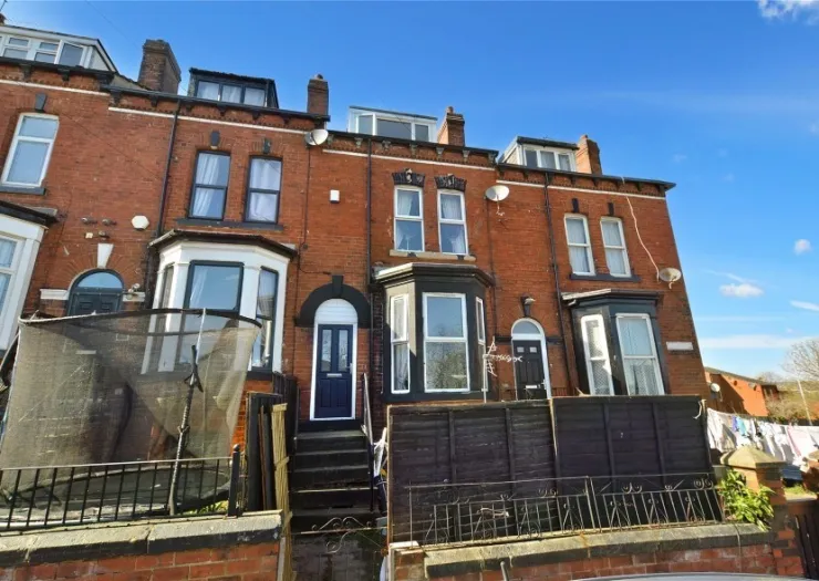 Red brick terraced houses with bay windows, under a blue sky.