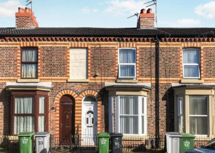 Red brick terraced houses with bay windows, white doors and wheelie bins.