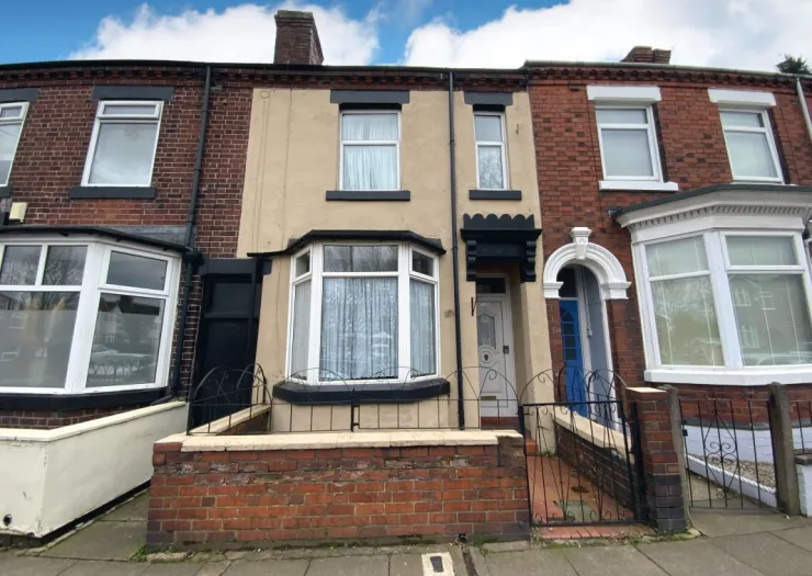 Beige terraced house exterior with bay window, black trim, and gated entrance.