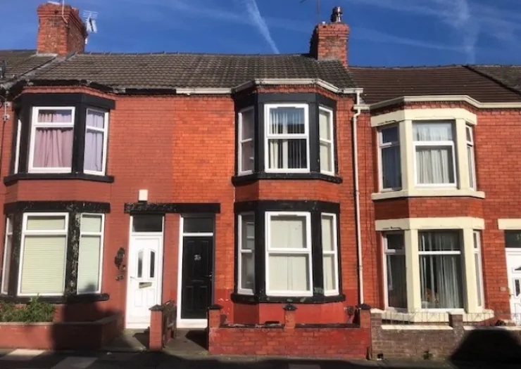Red brick terraced house with black and white trim, front garden, and bay windows.