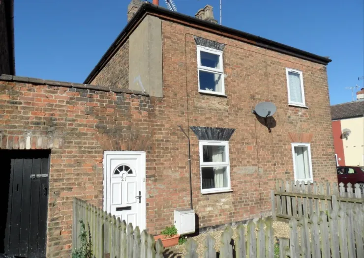 Exterior of a two-story brick house with white door and windows, under a clear blue sky.