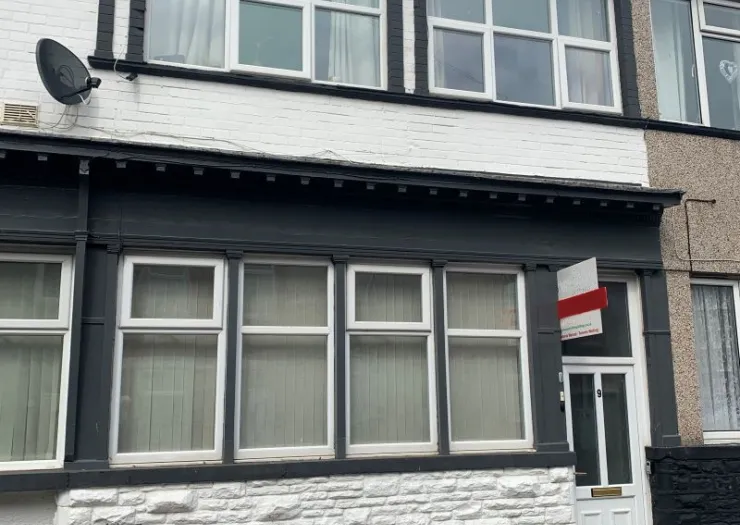 Residential property exterior with white windows, black trim, and a "To Let" sign.