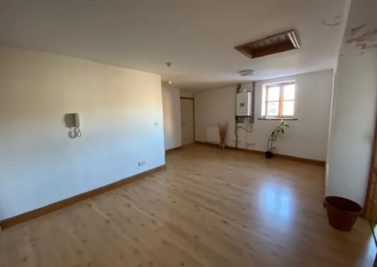 Empty room with light wood floors, white walls, a window, and a wall-mounted phone.