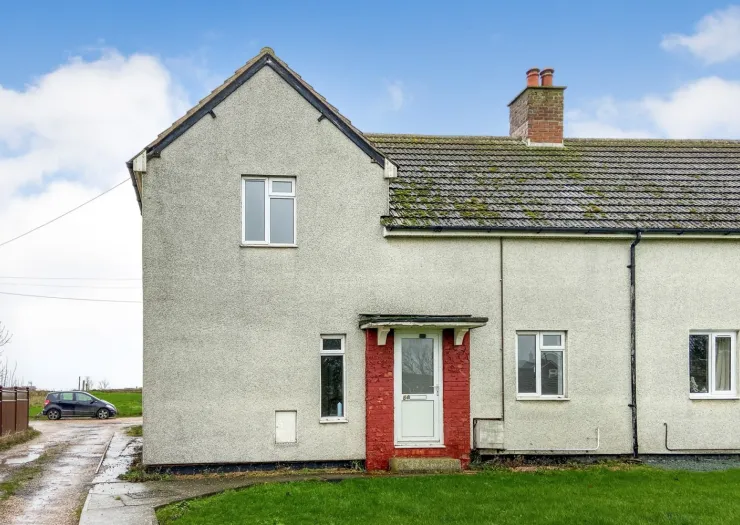 Semi-detached house with red brick porch, moss-covered roof, and driveway.