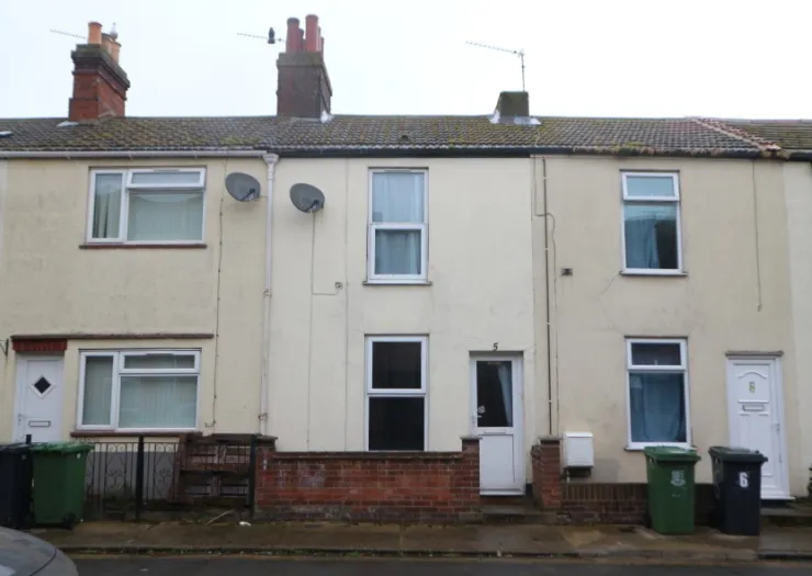 Cream terraced house exterior with white door and windows, and a low brick wall.