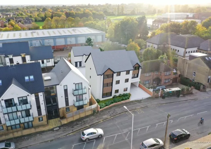 Modern white & gray apartment building, aerial view, street level perspective.